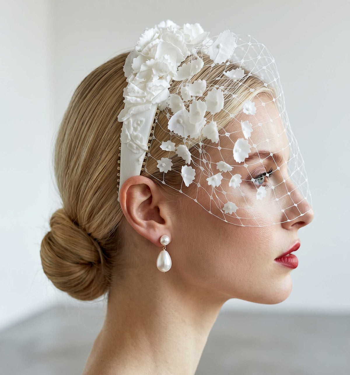 Serre-tête fleuri à voilette Pénélope porté de profil avec chignon — accessoire couture cérémonie — Les Majestés